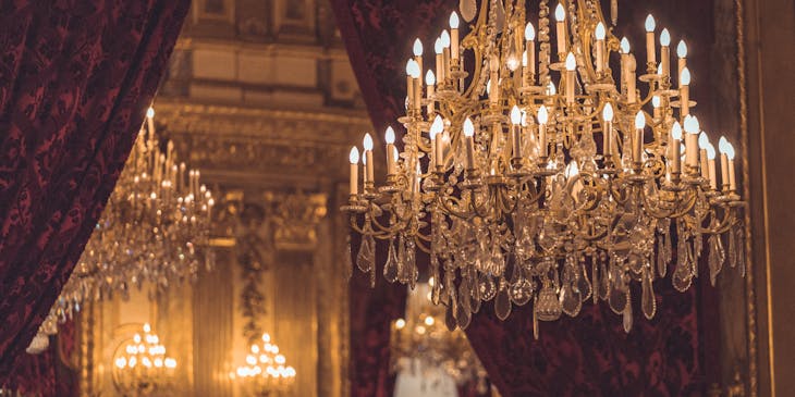 Elegant chandelier hanging with curtains in the background.