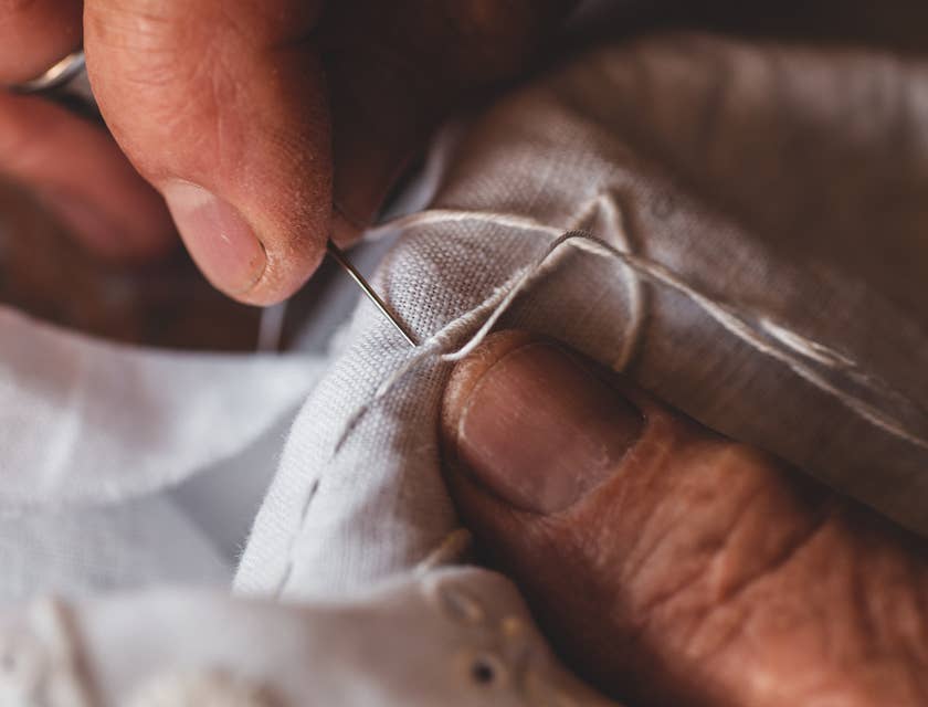 An embroiderer stitches with a needle.