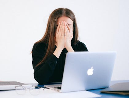 Mulher com as mãos no rosto depois que seu emprego foi encerrado ilegalmente.