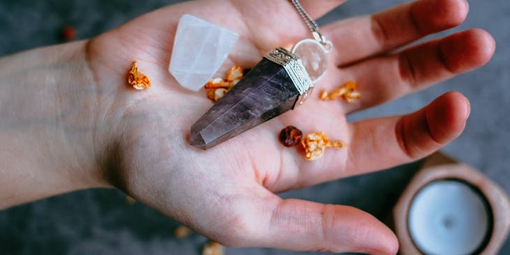 Person holding energy healing crystals and dried petals