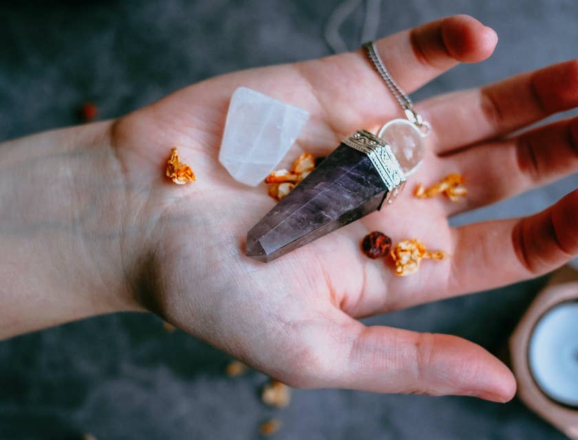 Person holding energy healing crystals and dried petals