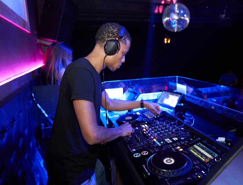 DJ operando um equipamento musical eletrônico em uma boate noturna.