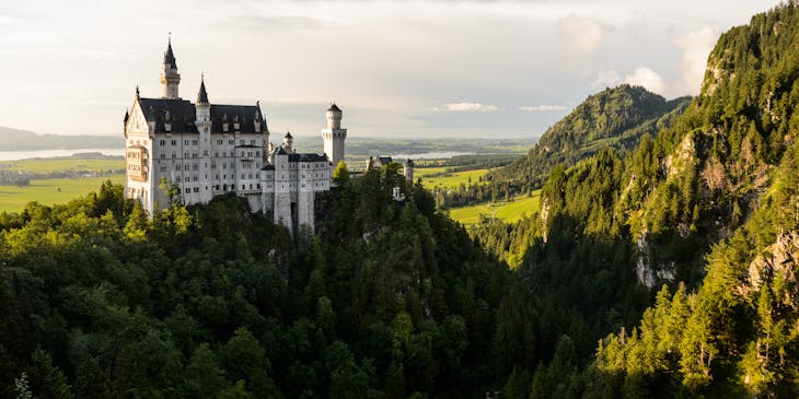 A white castle towers above the trees on a mountaintop