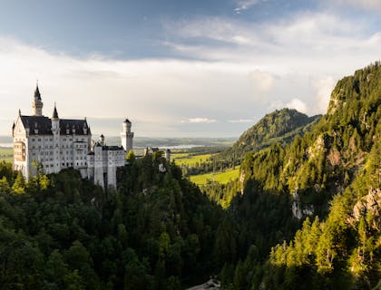 A white castle towers above the trees on a mountaintop