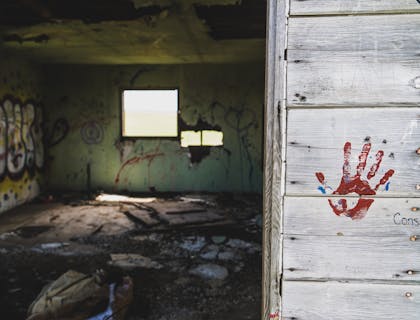Ein unheimlicher Escape-Room mit Graffiti-besprühten Wänden und einem roten Handabdruck am Eingang.