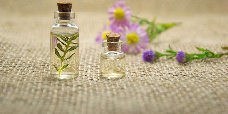 Essential oils in bottles with herbs and flowers.