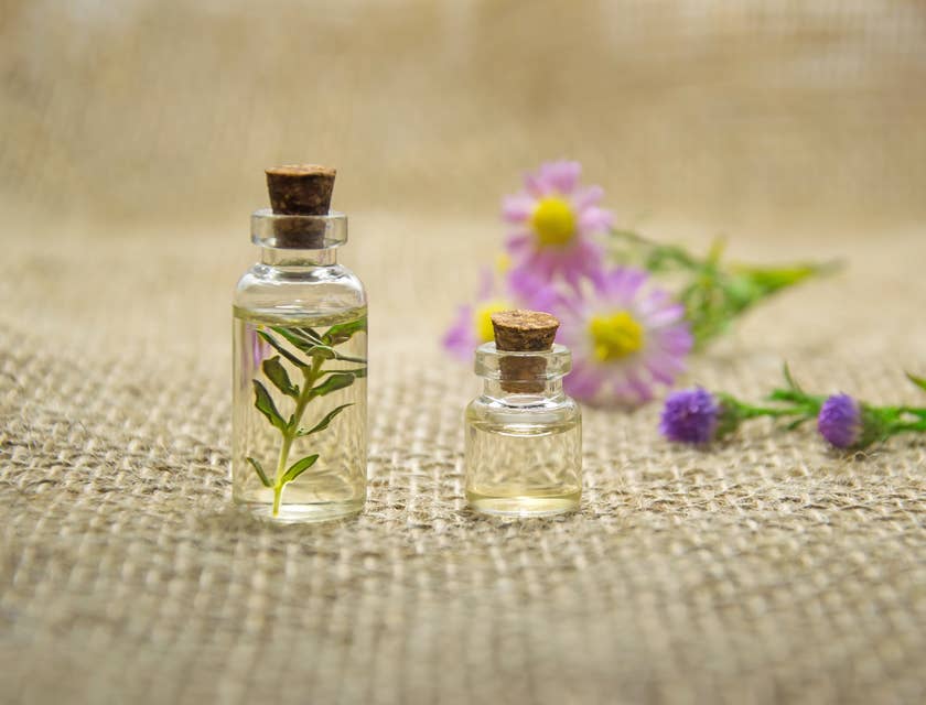 Oli essenziali in piccole bottigliette di vetro con fiori ed erbe.