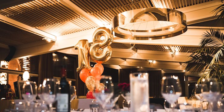 Table setting for an event with balloons in the background.