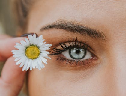 Una foto del ojo de una mujer junto a una flor blanca y amarilla en un negocio con nombre llamativo