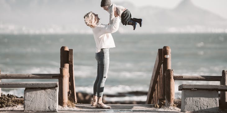 a mother carrying her son at the beach