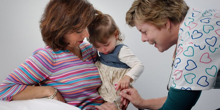 A nurse administers an injection to a child at a family practice.
