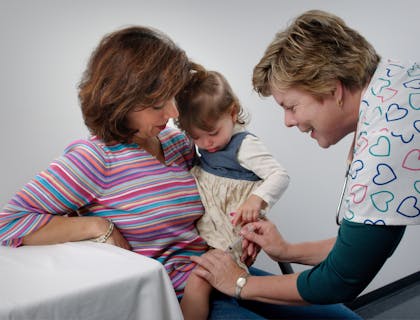 A nurse administers an injection to a child at a family practice.