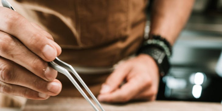 A chef adding the finer details to a fancy restaurant meal.