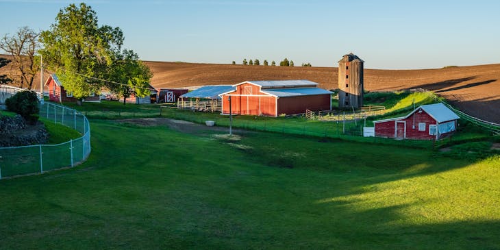 Farm yard with house, shed, grain storage, and outbuildings.