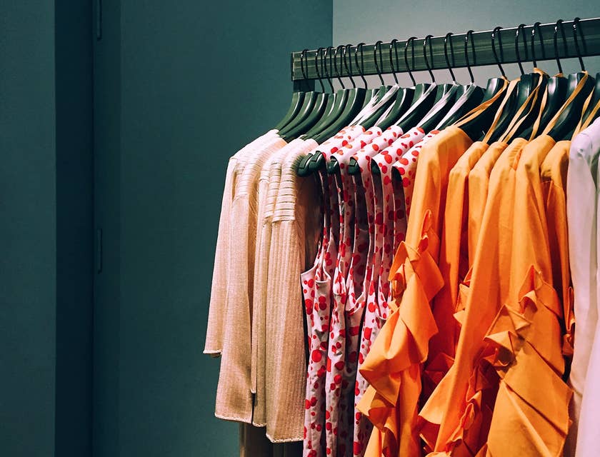 Estante de blusas y cárdigans de mujer agrupados por color y estilo en un negocio de moda.