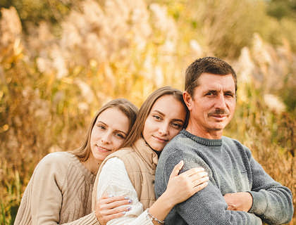 Un padre abrazado por sus dos hijas en un negocio de padre e hija.