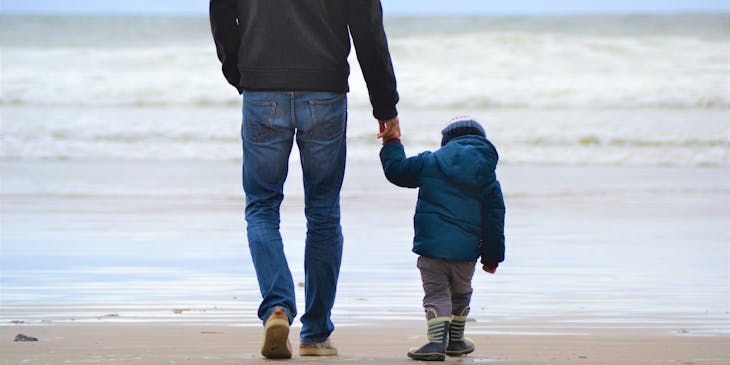 Father and son walking on a beach.