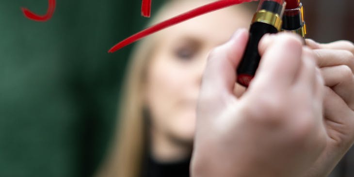 A female writing a message of empowerment with lipstick on a mirror.