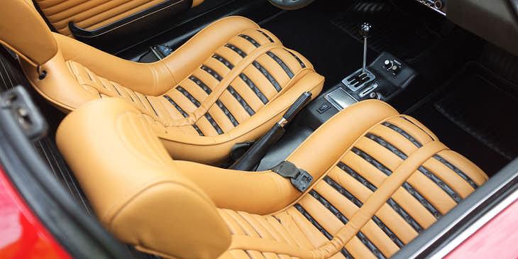 Interior of a red sports car with beige upholstery that has been added by an auto upholstery business.
