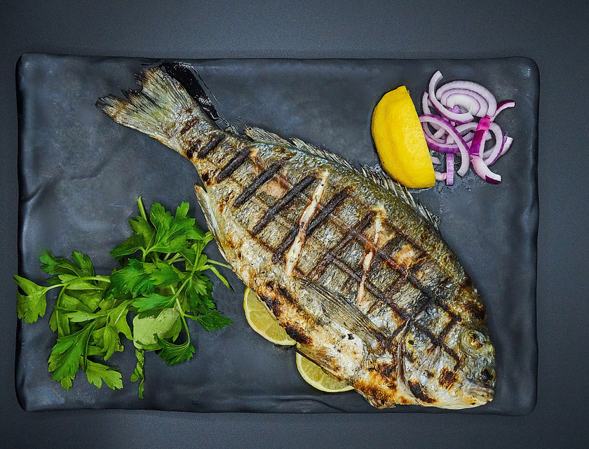 A grilled fish served on a plate in a fish restaurant.