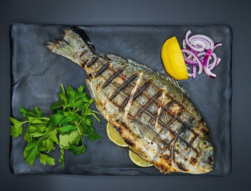 Un poisson grillé servi sur une assiette dans un restaurant de poissons.