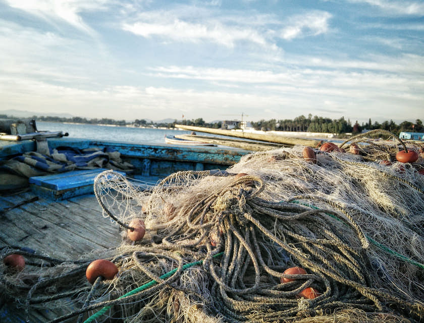 Delle reti da pesca sistemate accanto a una barca su una spiaggia.