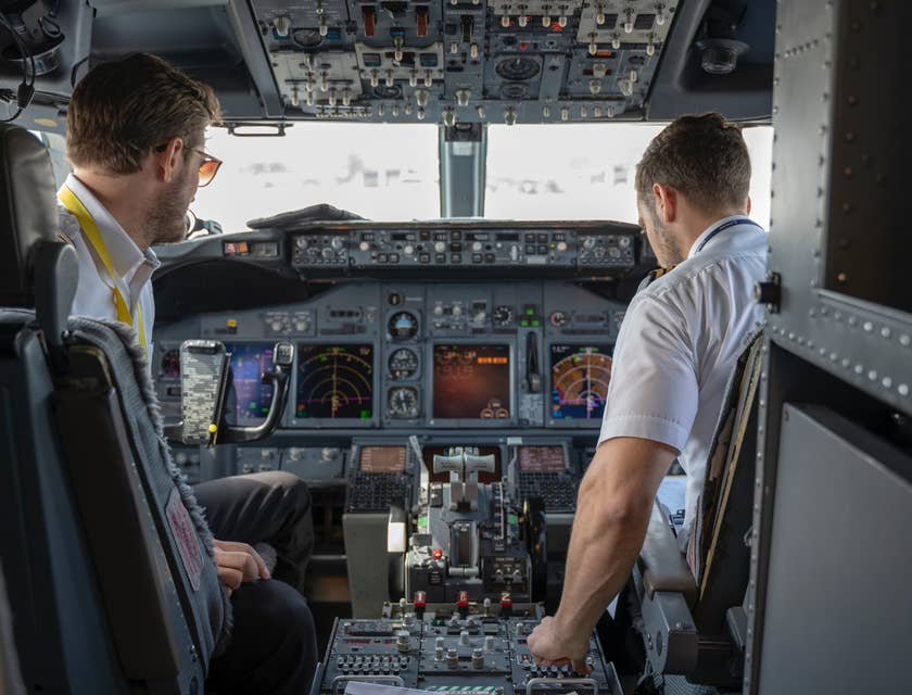 Um piloto e um copiloto na cabine de pilotagem de um avião.