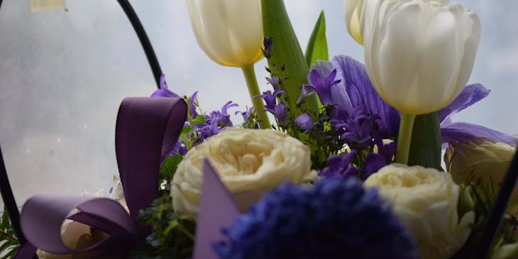 A floral arrangement with a purple ribbon created by floral designer.