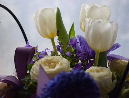 Arreglo floral con flores blancas y moradas en un negocio de diseñadores florales