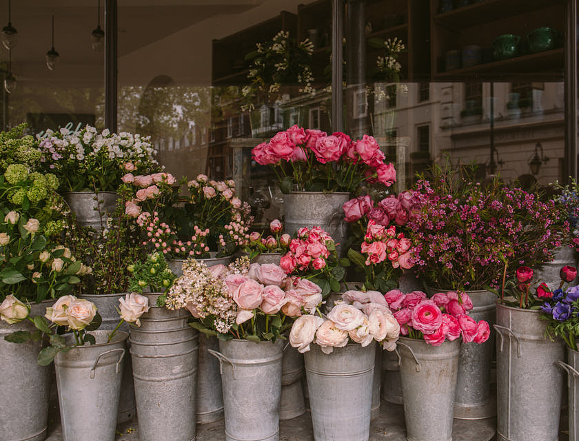 Cubetas de flores rosas y azules afuera de una florería.