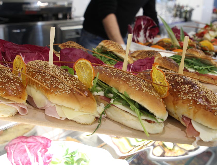 Panini farciti serviti su un vassoio sopra una vetrina illuminata di un food stand.