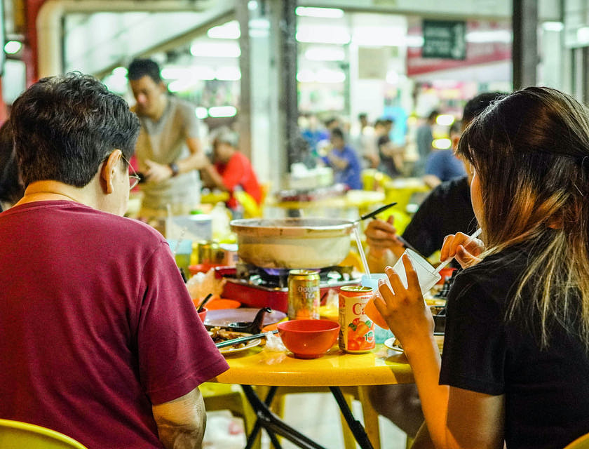 Personnes assises à une table dans un food court.
