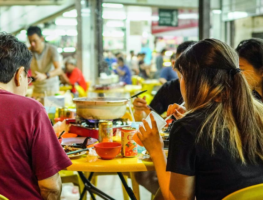 Besucher eines Food-Courts sitzen mit dem Rücken zur Kamera und genießen ein Mittagessen in entspannter Atmosphäre.
