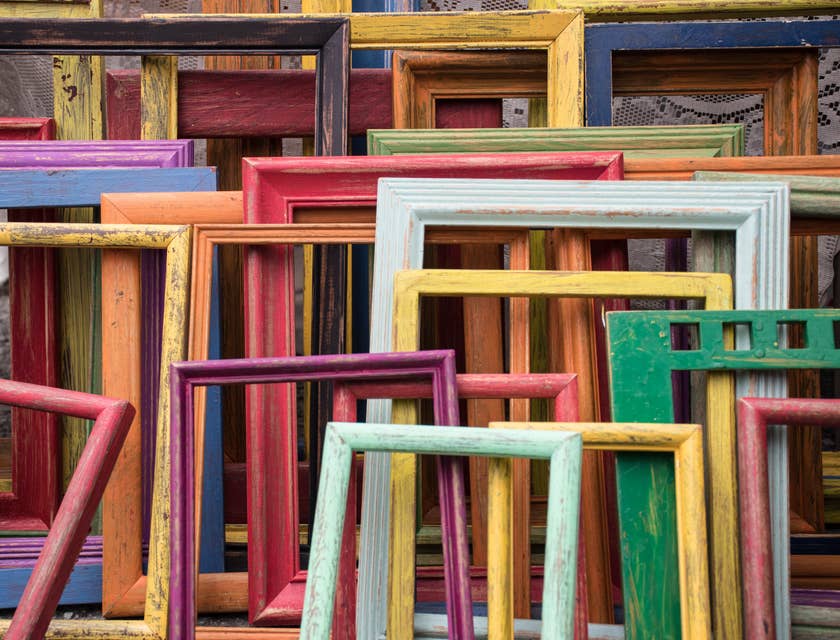 Delle cornici di vari colori appoggiate a una parete di un negozio di cornici.