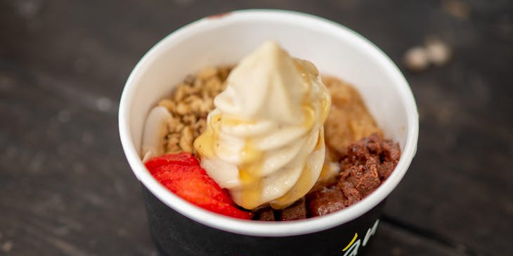 A serving of frozen yogurt with an assortment of accompaniments.