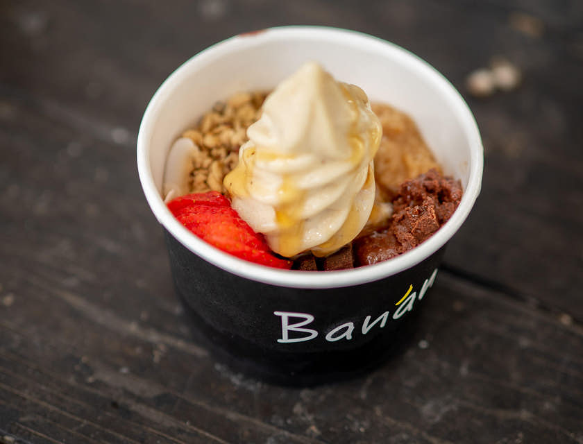 Una porción de yogurt helado servido con toppings en un vaso en un negocio de yogurt helado.