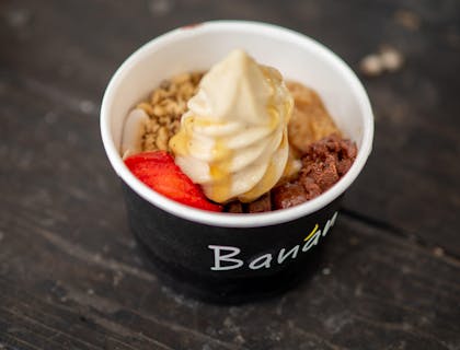 Una porción de yogurt helado servido con toppings en un vaso en un negocio de yogurt helado.