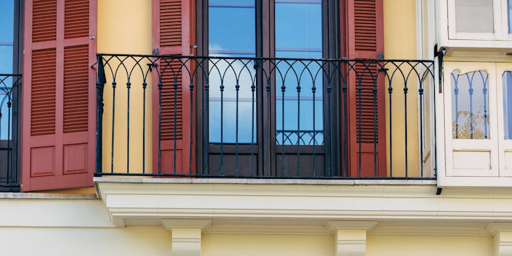 A building with a funky painting on window shutters.