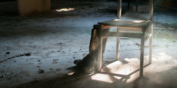 A broken wooden chair abandoned in an empty building.