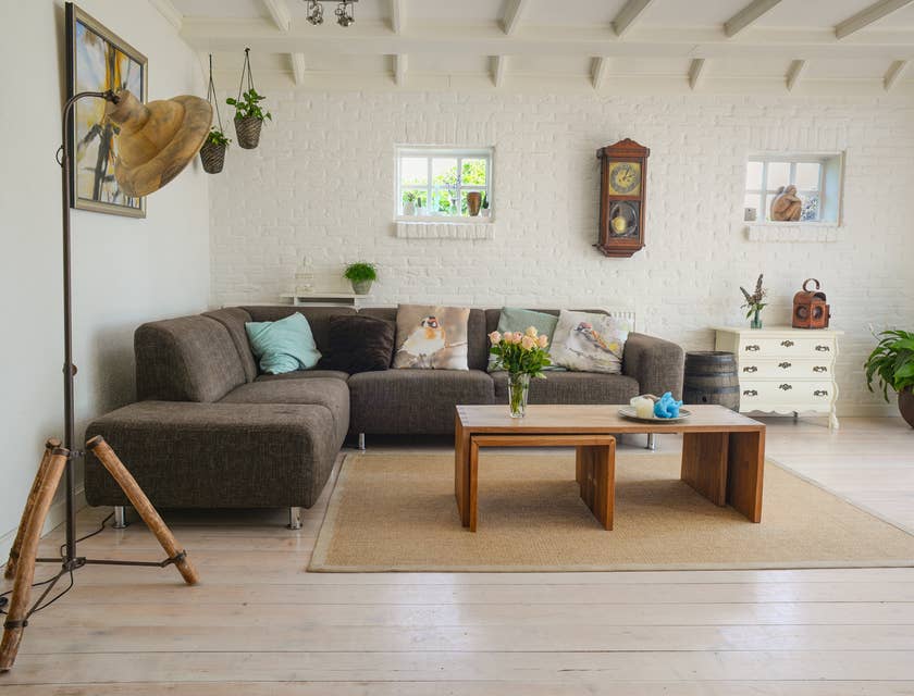 Ein Raum in einem Möbelladen ist mit einem grauen Sofa, einem Holztisch und Pflanzen ausgekleidet.