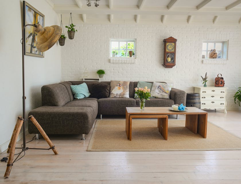 Brown sectional couch against a wall with a coffee table, light, and ornaments around it set up in a furniture store.