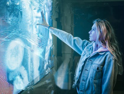 Mulher tocando um painel de luz de aparência futurista.