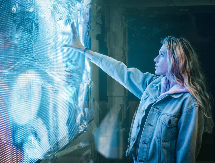 Una donna che tocca un pannello di luce bianca e blu dall'aspetto futuristico.