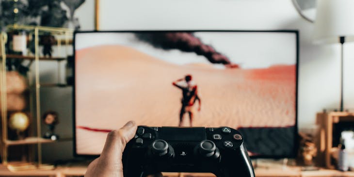 Person holding a gaming console remote in front of a television screen.