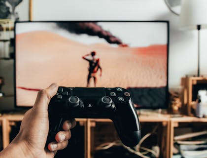 Person holding a gaming console remote in front of a television screen.