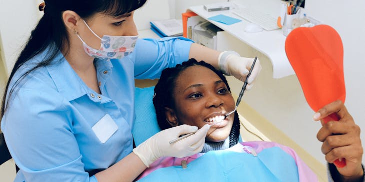 General dentist showing a smiling patient her teeth in a mirror.