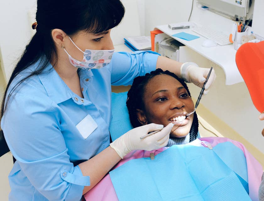 Paciente sendo atendida e sorrindo para um espelho em uma clínica odontológica.