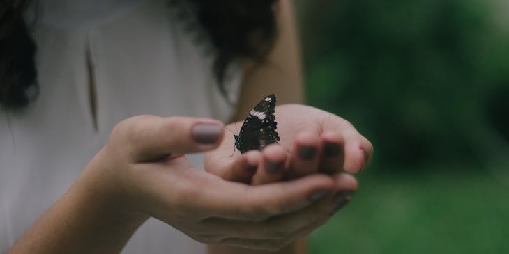 A woman gently holding a fragile butterfly.