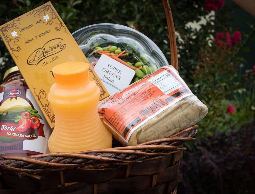 Un cesto regalo con succo di frutta e altre pietanze.