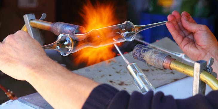 Un soffiatore che crea un oggetto in vetro soffiato in una soffieria.